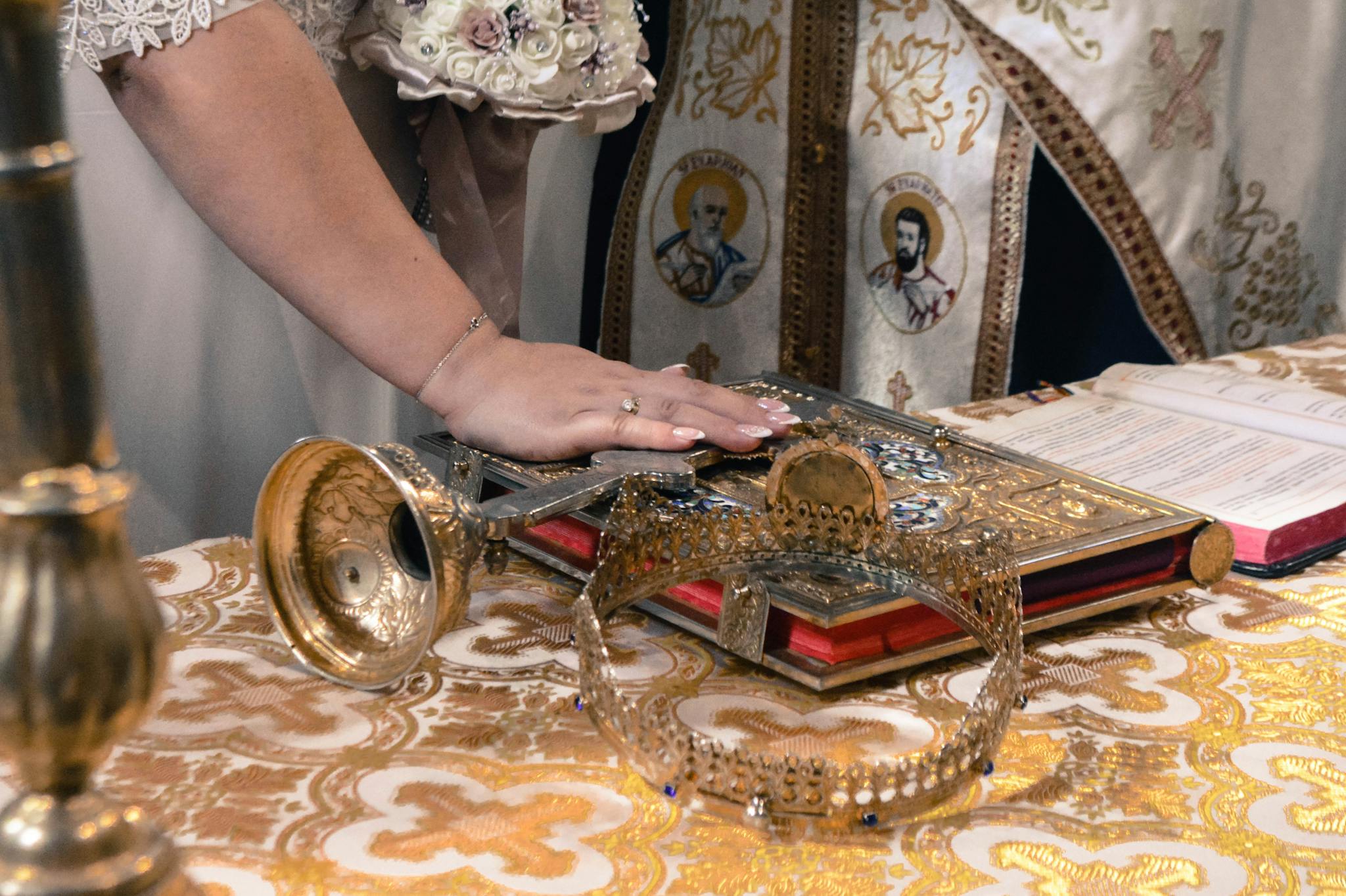 A bride's hand on a religious book during an Orthodox wedding ceremony, showcasing traditional artifacts.