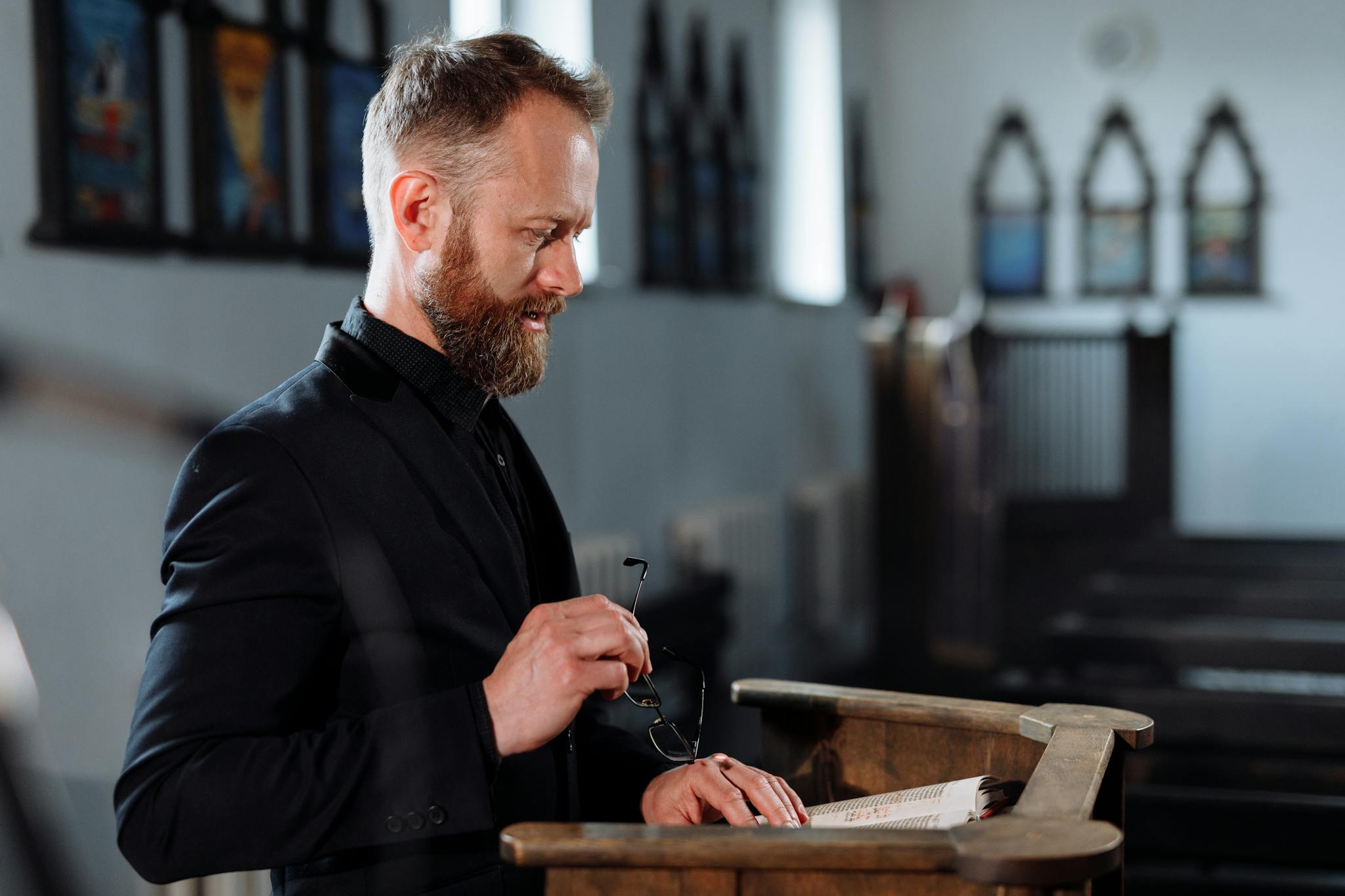 A priest stands at a pulpit, delivering a sermon in a church setting.